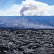 volcanic terrain in the foreground and smoke in the background from Mauna Loa eruption