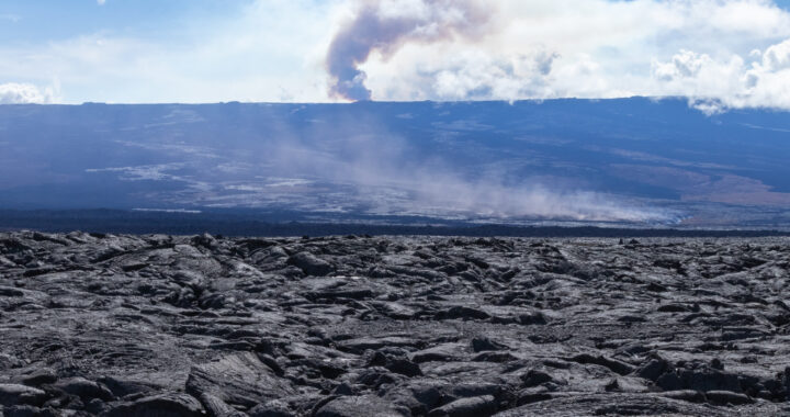 volcanic terrain in the foreground and smoke in the background from Mauna Loa eruption